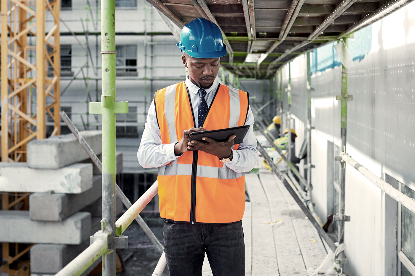 Construction worker looking down at a tablet device at a construction site. 