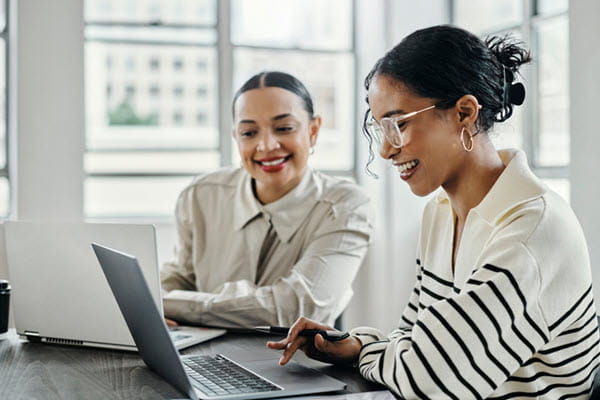 Two businesswomen working on laptops.