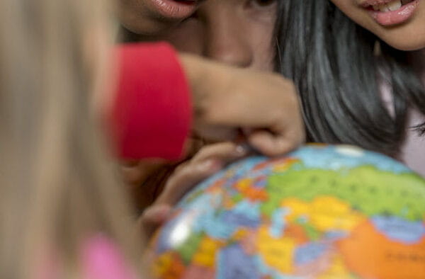 Kids looking at a globe and pointing to different countries.