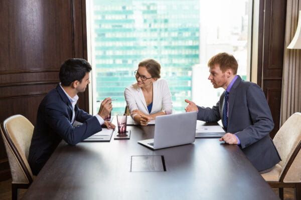 two men and a woman in a conference room