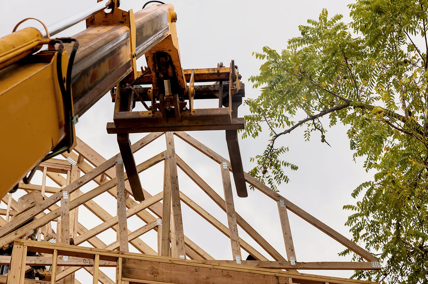 Crane moving a wooden frame for a house.