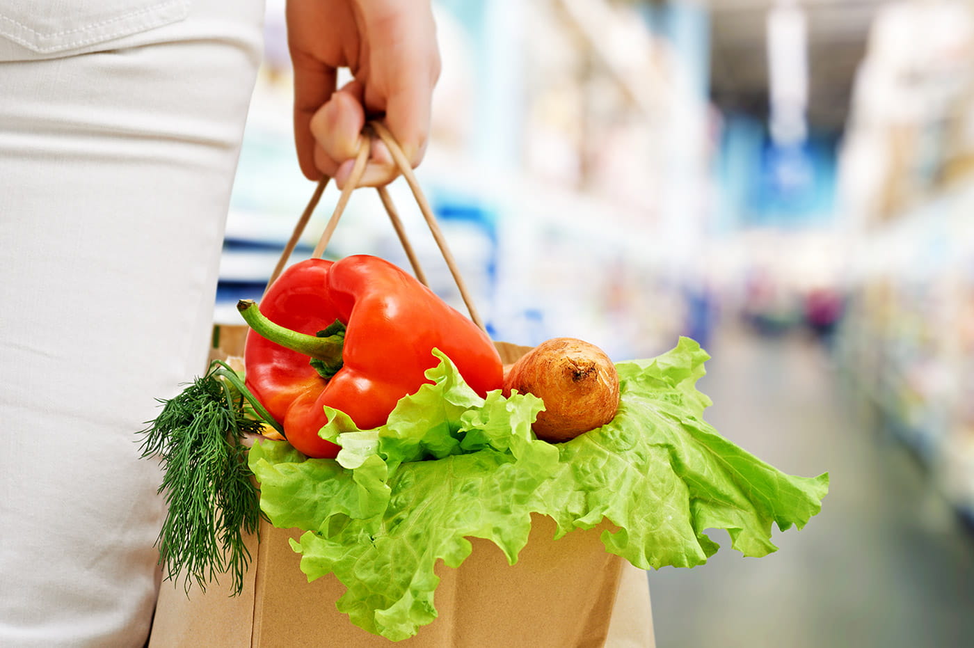 Paper grocery bag with various vegetables sticking out of the top.