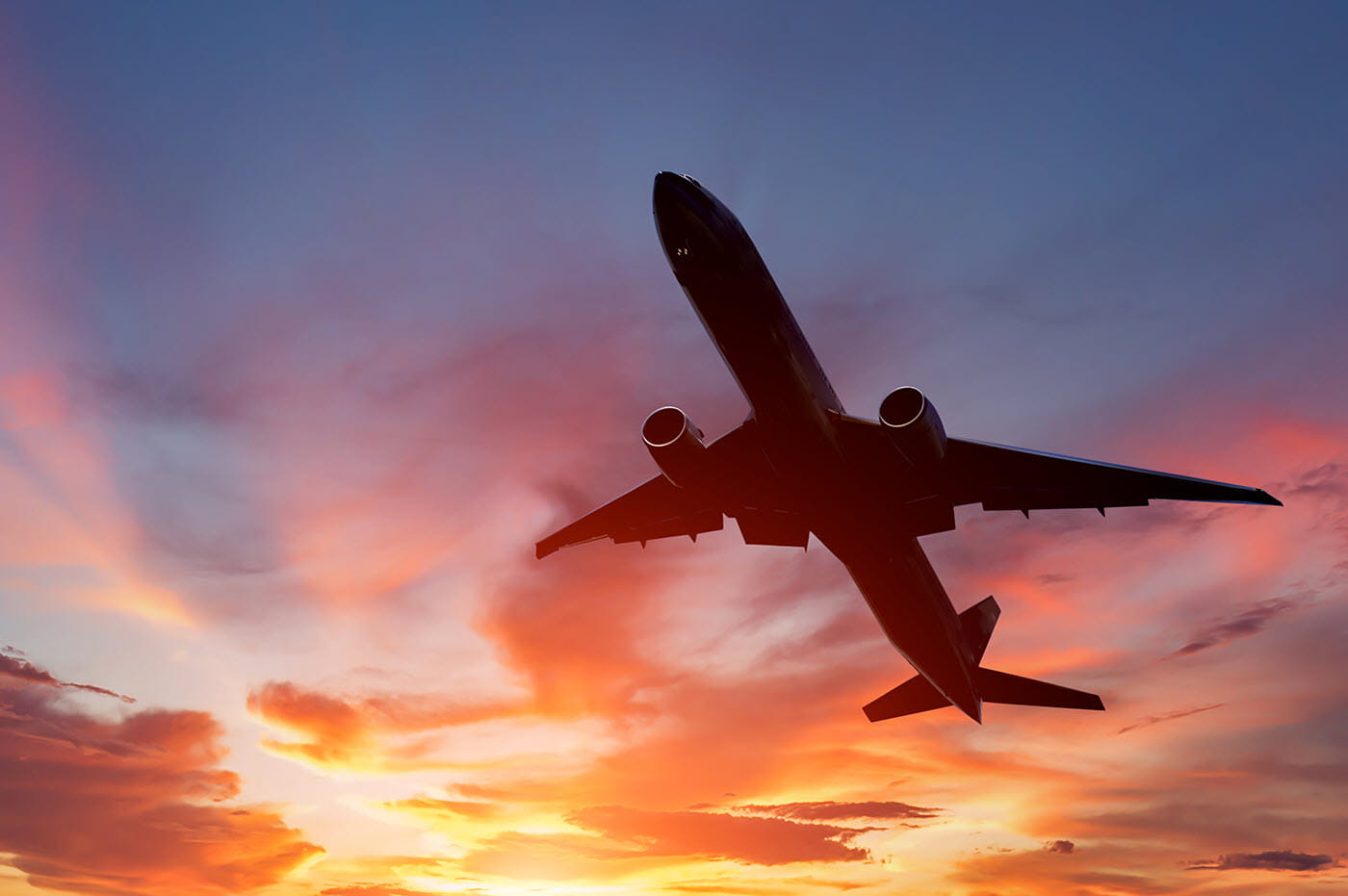 An airplane flying in front of a sunset.