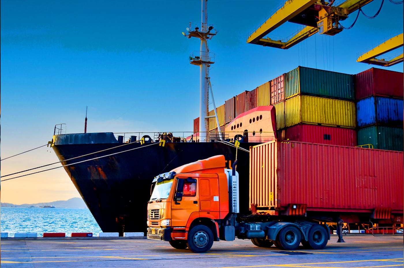 Freight boxes with a loading truck in front of them on a ship dock 