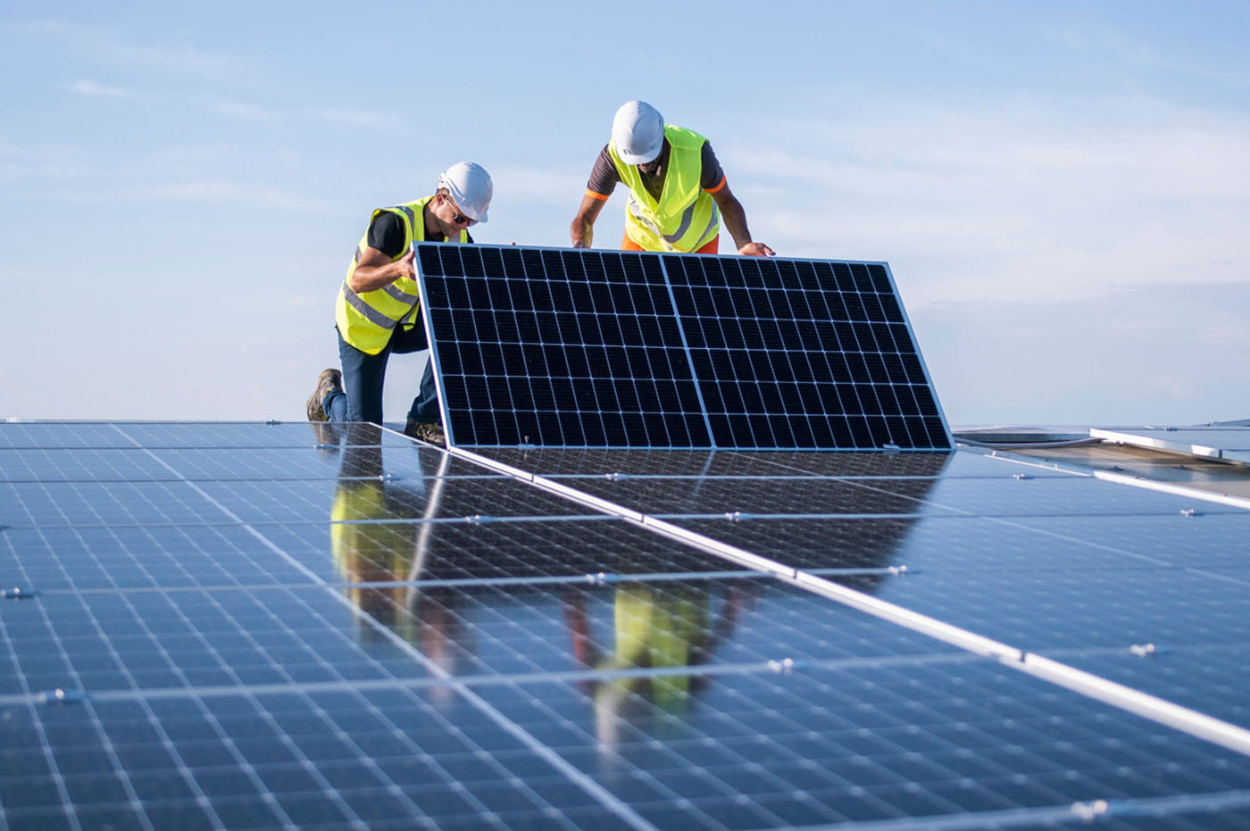 Two utility workers installing a solar panel on a roof.